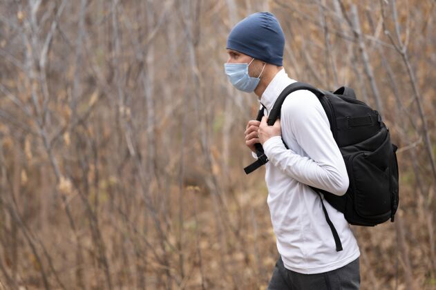运动带着面具和背包的中枪男子在树林里小径跑步健身