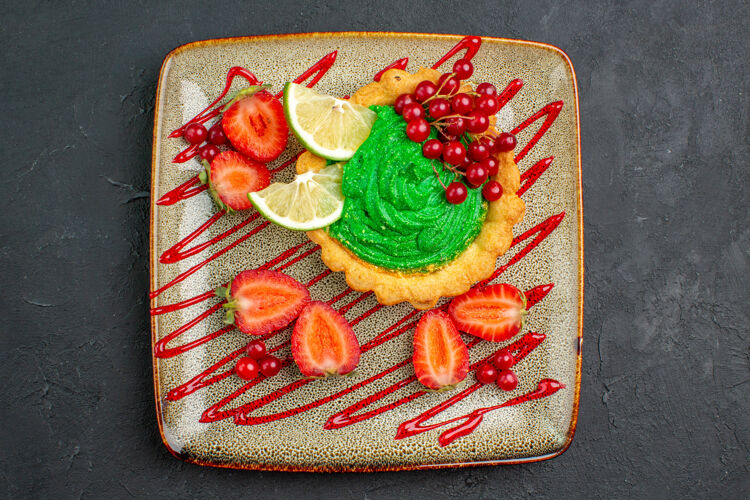 顶部顶视图美味的蛋糕与绿色奶油和草莓在黑暗的背景甜甜点茶蛋糕容器美味