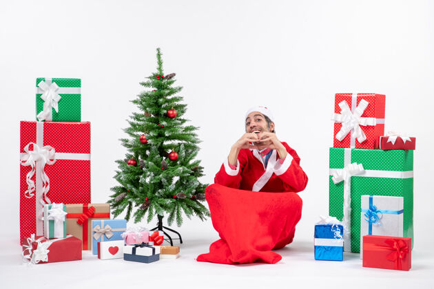 盒子有趣的年轻人庆祝新年或圣诞节假期坐在地上附近的礼物和装饰圣诞树礼物男人装饰