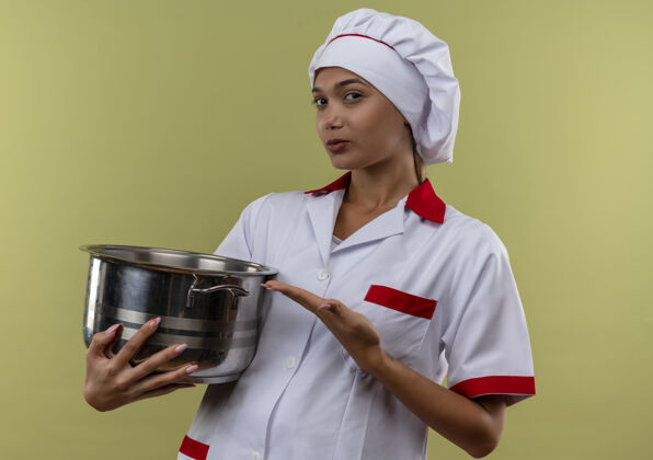 厨师年轻的女厨师穿着厨师制服 在孤立的绿色墙上展示手中的平底锅年轻平底锅展示