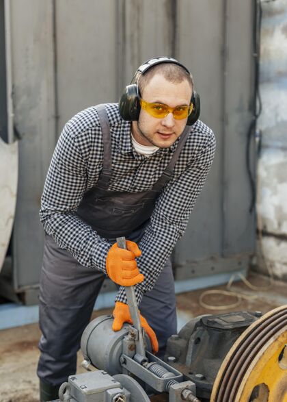 职业戴着安全眼镜和耳机的工人的前视图人垂直职业