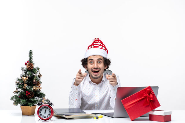 成年人好奇的年轻商人戴着滑稽的圣诞老人帽 在白色背景下询问办公室里的一些事情微笑办公室礼物