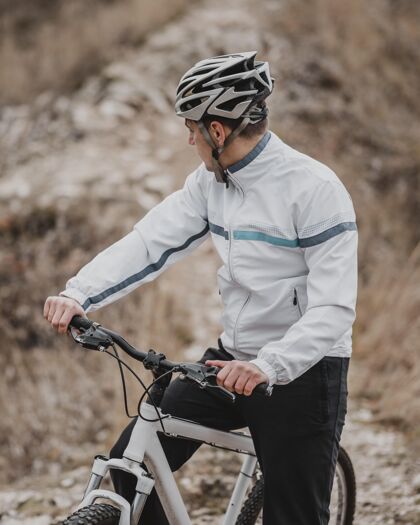 运动一个男人在寒冷的日子里骑着自行车 看着别处自行车运动活动